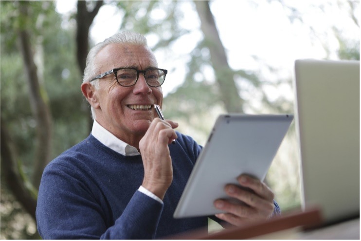 Homme âgé souriant tenant une tablette